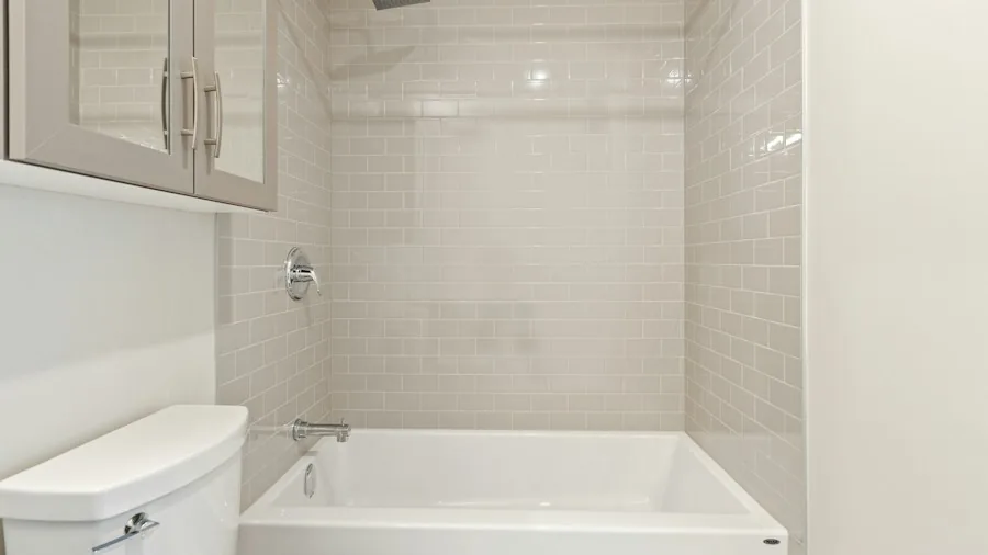 Budget Bathroom Upgrade: How to Refinish a Bathtub and Add Stone Tiles in One Weekend 2 white painted bathtub shower surround